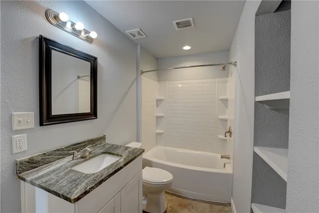 a bathroom with a granite countertop sink toilet and shower