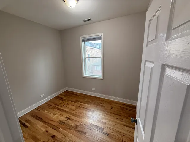 an empty room with wooden floor cabinet and windows