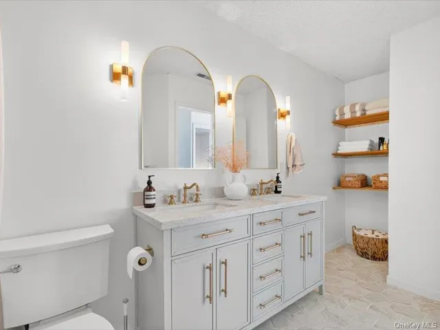 a bathroom with a double vanity sink toilet and a mirror