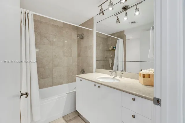 a bathroom with a sink vanity granite tub shower and a mirror