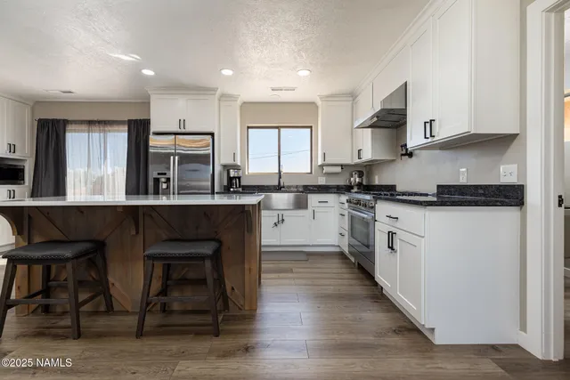 a kitchen with stainless steel appliances a table chairs refrigerator and microwave