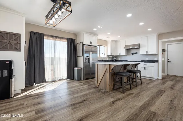 a kitchen with stainless steel appliances granite countertop a stove a sink dishwasher a refrigerator and a oven with wooden floor