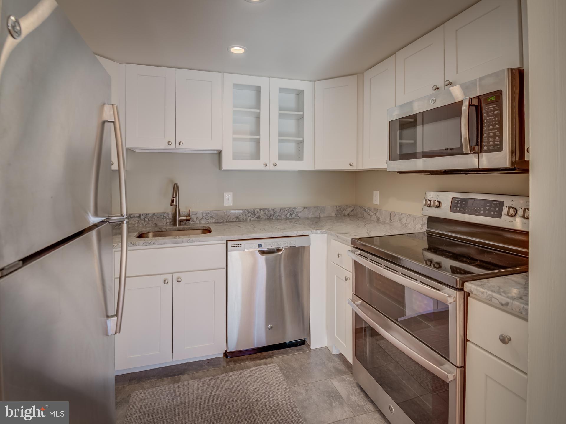 3210 Grace Street Northwest, Unit 309 Washington, DC 20007 - Photo 13 of 43 a kitchen with granite countertop white cabinets and stainless steel appliances