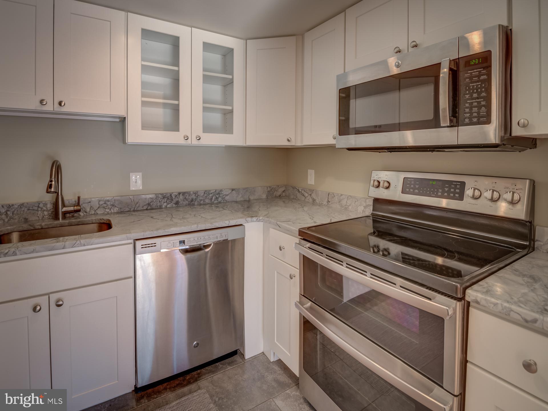 3210 Grace Street Northwest, Unit 309 Washington, DC 20007 - Photo 14 of 43 a kitchen with granite countertop white cabinets and stainless steel appliances