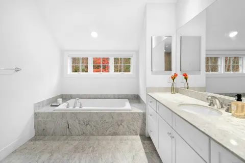 a spacious bathroom with a tub sink and mirror
