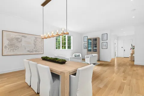 a kitchen with stainless steel appliances kitchen island a white table chairs and window