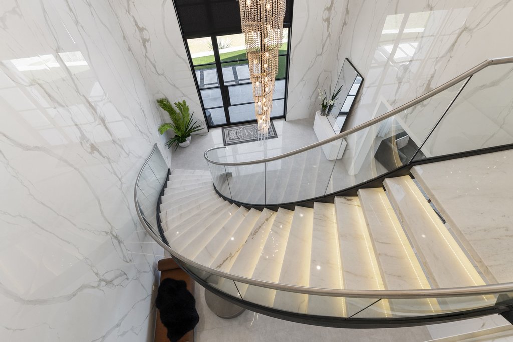 7117 Davenport Divide Road Austin, TX 78738 - Photo 33 of 40 A grand, curving staircase with illuminated treads creates a dramatic entrance, complemented by sleek glass railings.