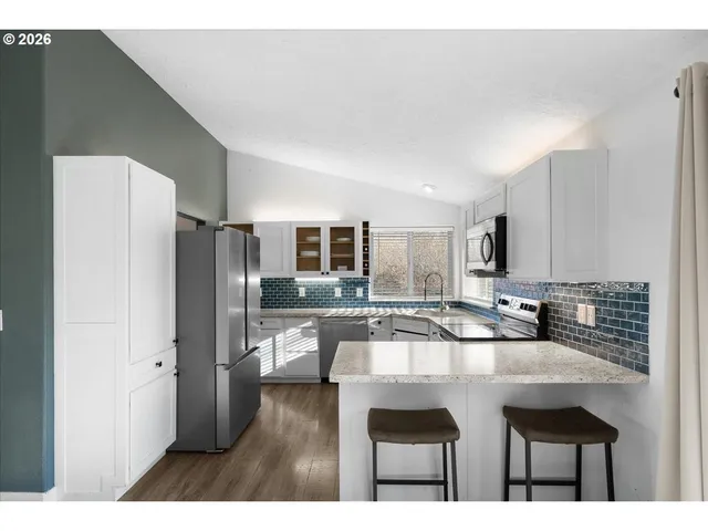 a kitchen with stainless steel appliances kitchen island granite countertop a refrigerator and a stove top oven