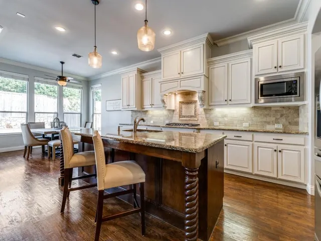 a kitchen with granite countertop a table chairs microwave and cabinets
