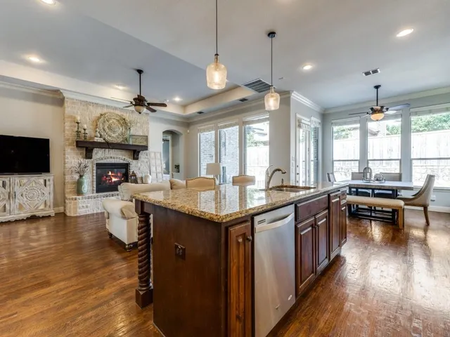 a kitchen with granite countertop a stove top oven a sink dishwasher and a dining table with wooden floor