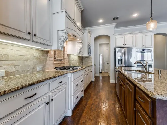 a large kitchen with granite countertop lots of counter space and stainless steel appliances