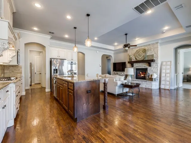 a large open kitchen with stainless steel appliances kitchen island granite countertop a large center island and a wooden floors