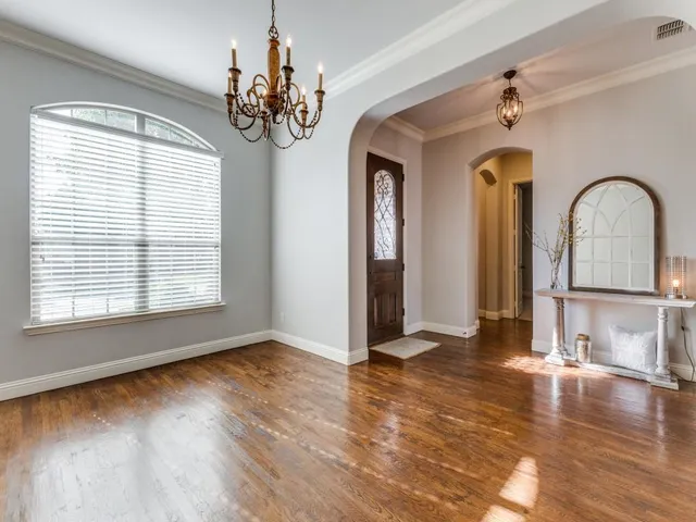 a view of a livingroom with wooden floor a chandelier and windows