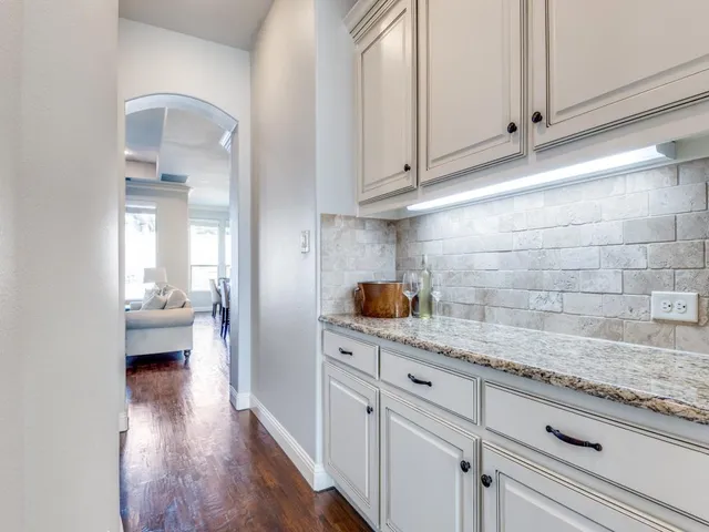 a kitchen with granite countertop white cabinets and a wooden floor