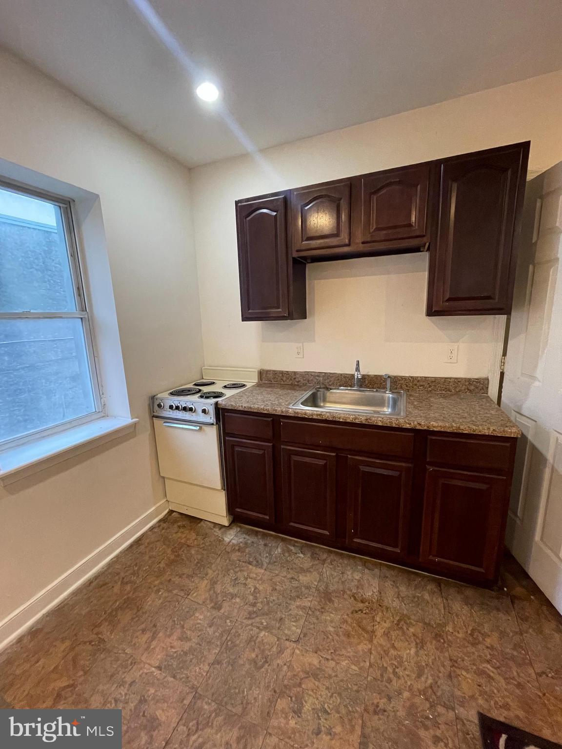 3427 North 2nd Street, Unit 2R Philadelphia, PA 19140 - Photo 3 of 5 a kitchen with granite countertop a stove and a wooden cabinets