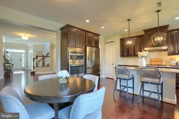 a kitchen with kitchen island granite countertop a stove a sink a dining table and chairs with wooden floor