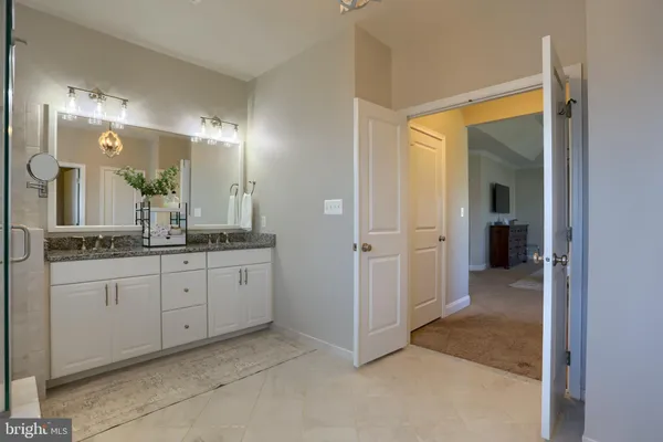 a spacious bedroom with a bed and a lamp on the dresser