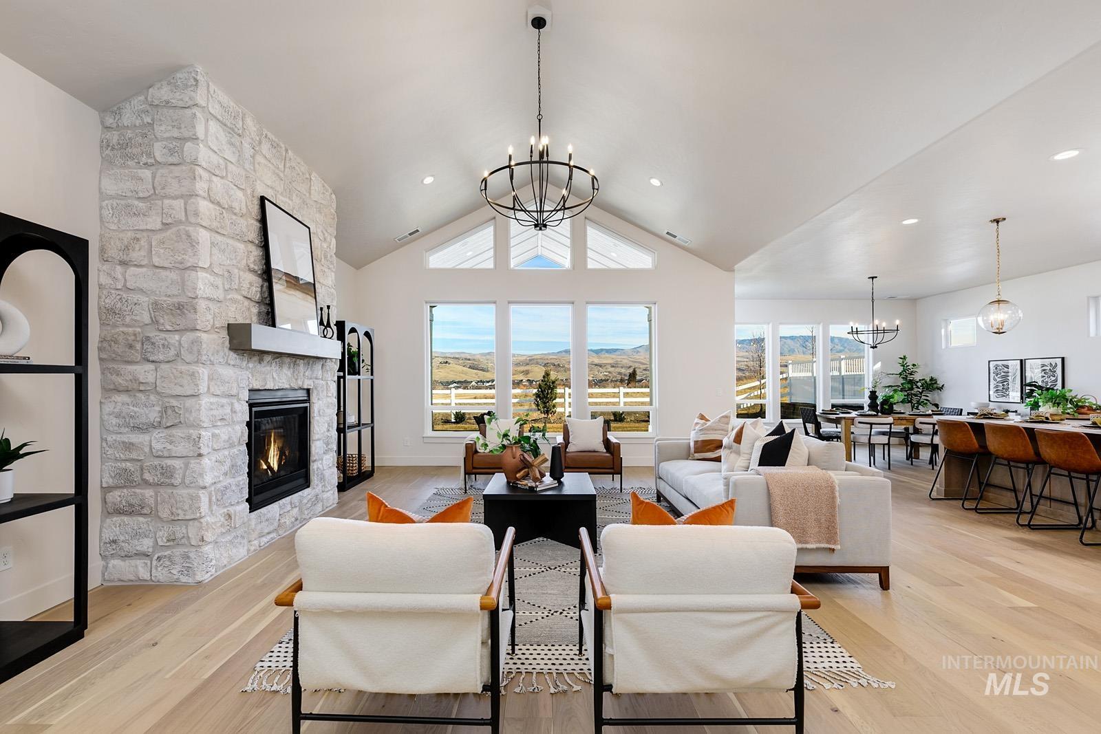 13660 North Spring Creek Way Boise, ID 83714 - Photo 2 of 42 Living area featuring suspended lighting, a stone fireplace, light wood-type flooring, lofted ceiling, and a mountain view