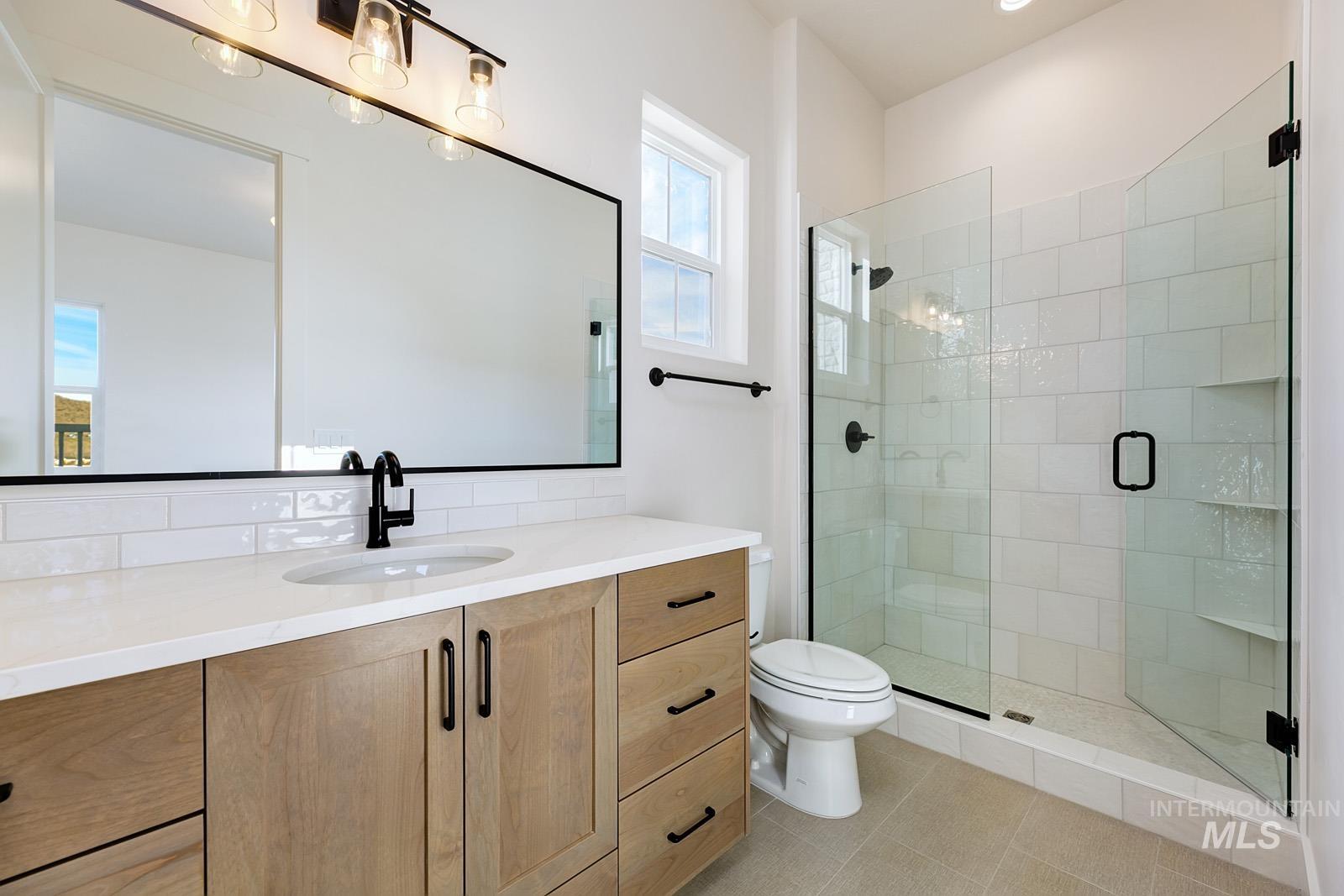 13660 North Spring Creek Way Boise, ID 83714 - Photo 22 of 42 Full bathroom featuring vanity, a shower stall, light tile patterned floors, and tasteful backsplash