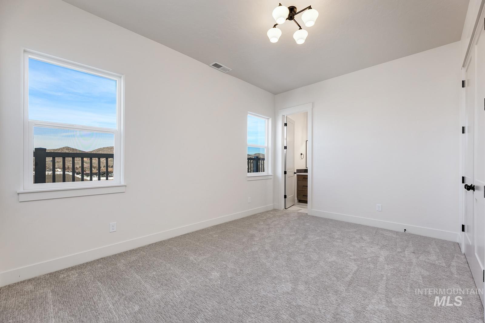 13660 North Spring Creek Way Boise, ID 83714 - Photo 23 of 42 Unfurnished bedroom featuring carpet floors, ensuite bathroom, and a chandelier
