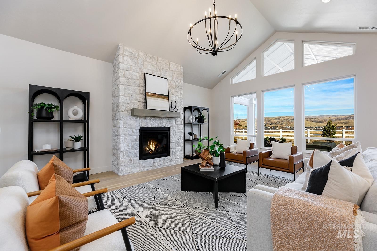 13660 North Spring Creek Way Boise, ID 83714 - Photo 3 of 42 Living area featuring a fireplace, wood finished floors, a chandelier, a high ceiling, and a mountain view