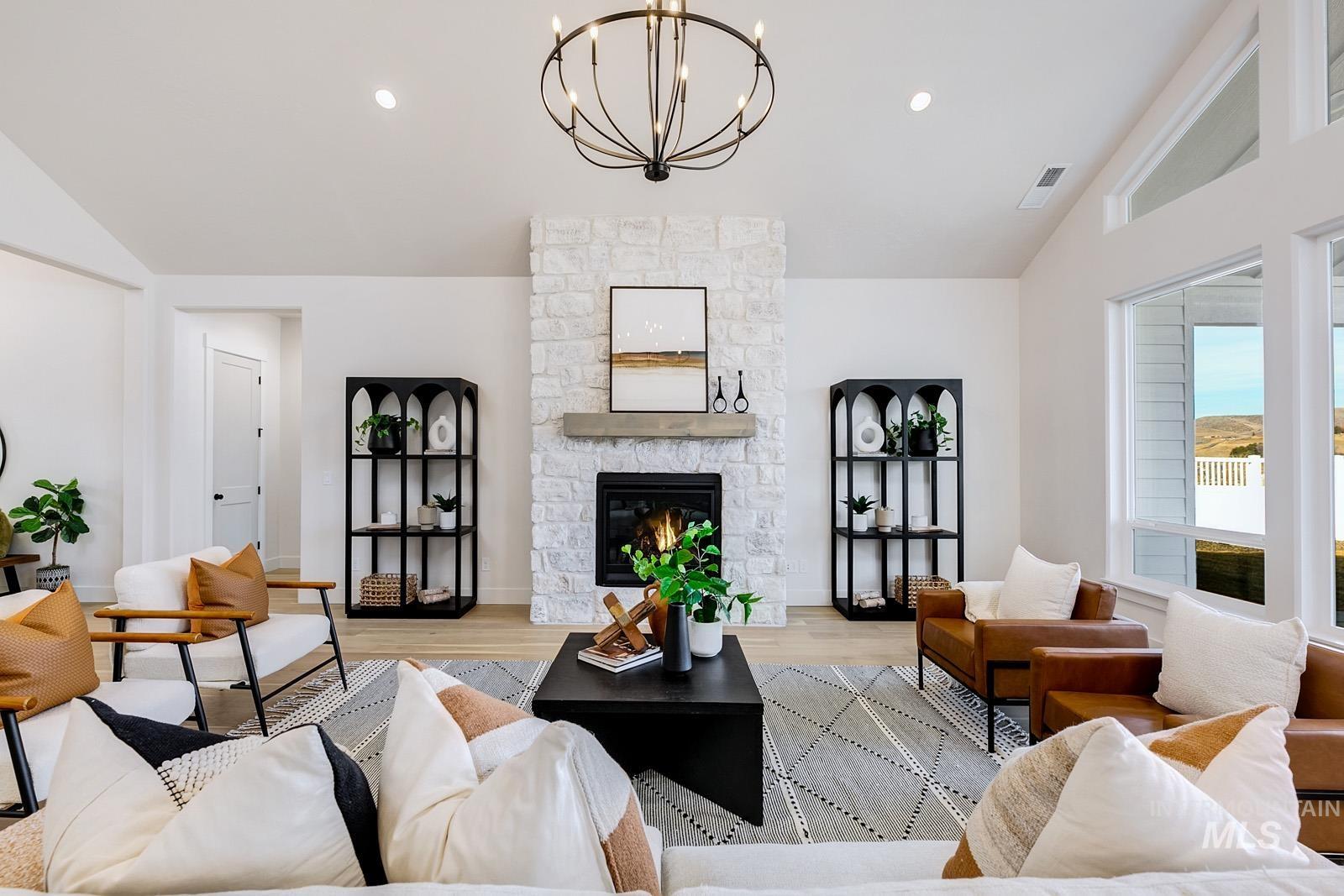 13660 North Spring Creek Way Boise, ID 83714 - Photo 4 of 42 Living room with lofted ceiling, light wood-style floors, a stone fireplace, and a chandelier