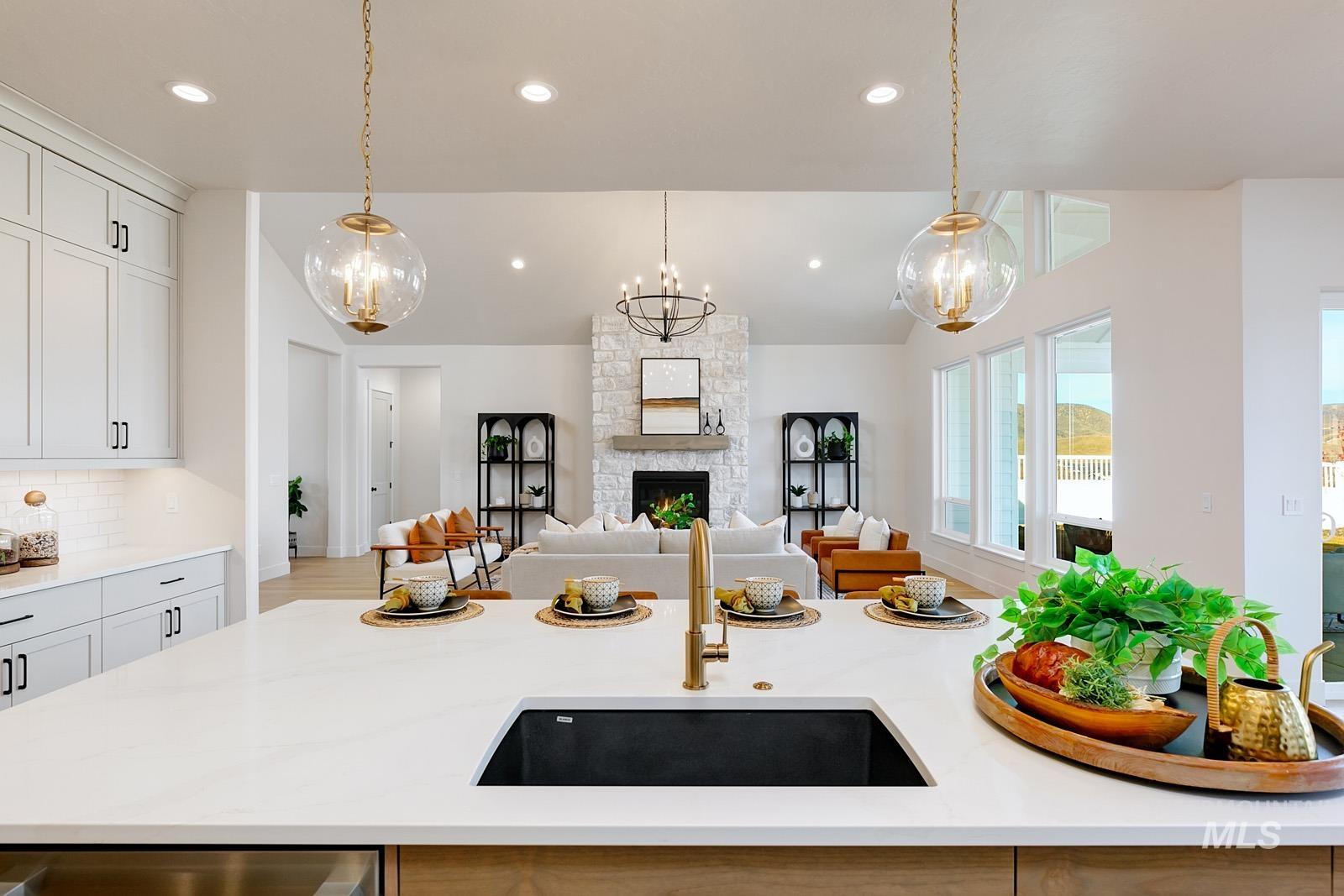 13660 North Spring Creek Way Boise, ID 83714 - Photo 42 of 42 Kitchen featuring light stone countertops, a fireplace, open floor plan, decorative backsplash, and a kitchen island with sink