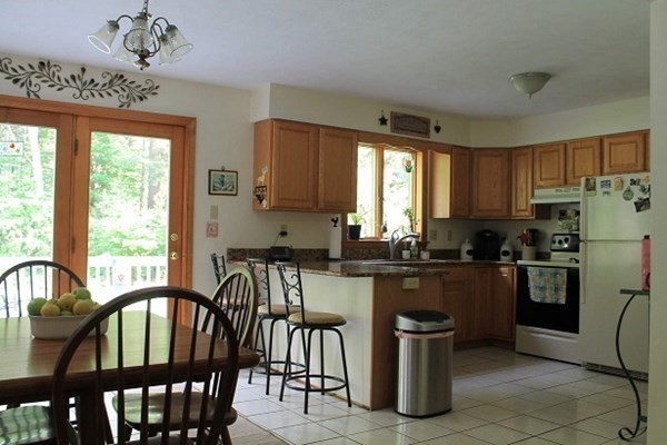 332 Lower Hampden Road Monson, MA 01057 - Photo 7 of 30 a kitchen with stainless steel appliances granite countertop a stove top oven a sink dishwasher a dining table and chairs with wooden floor