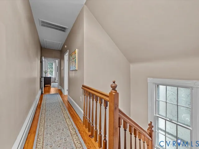 a view of a hallway with wooden floor and staircase