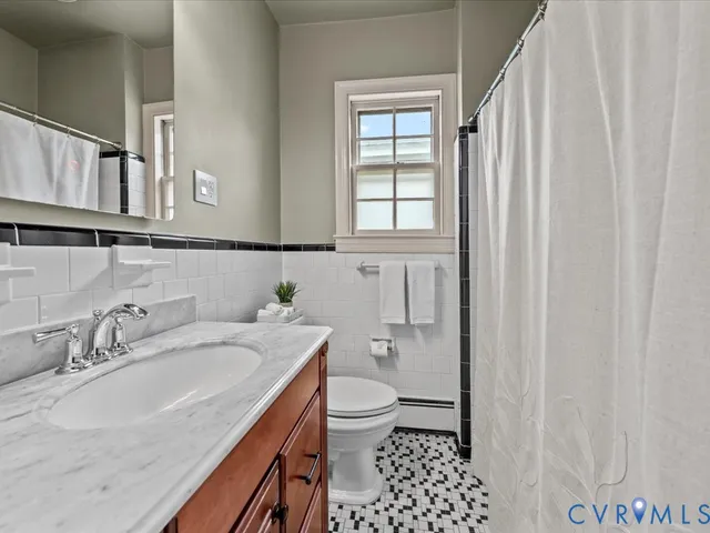 a bathroom with a granite countertop sink a toilet and a shower curtain