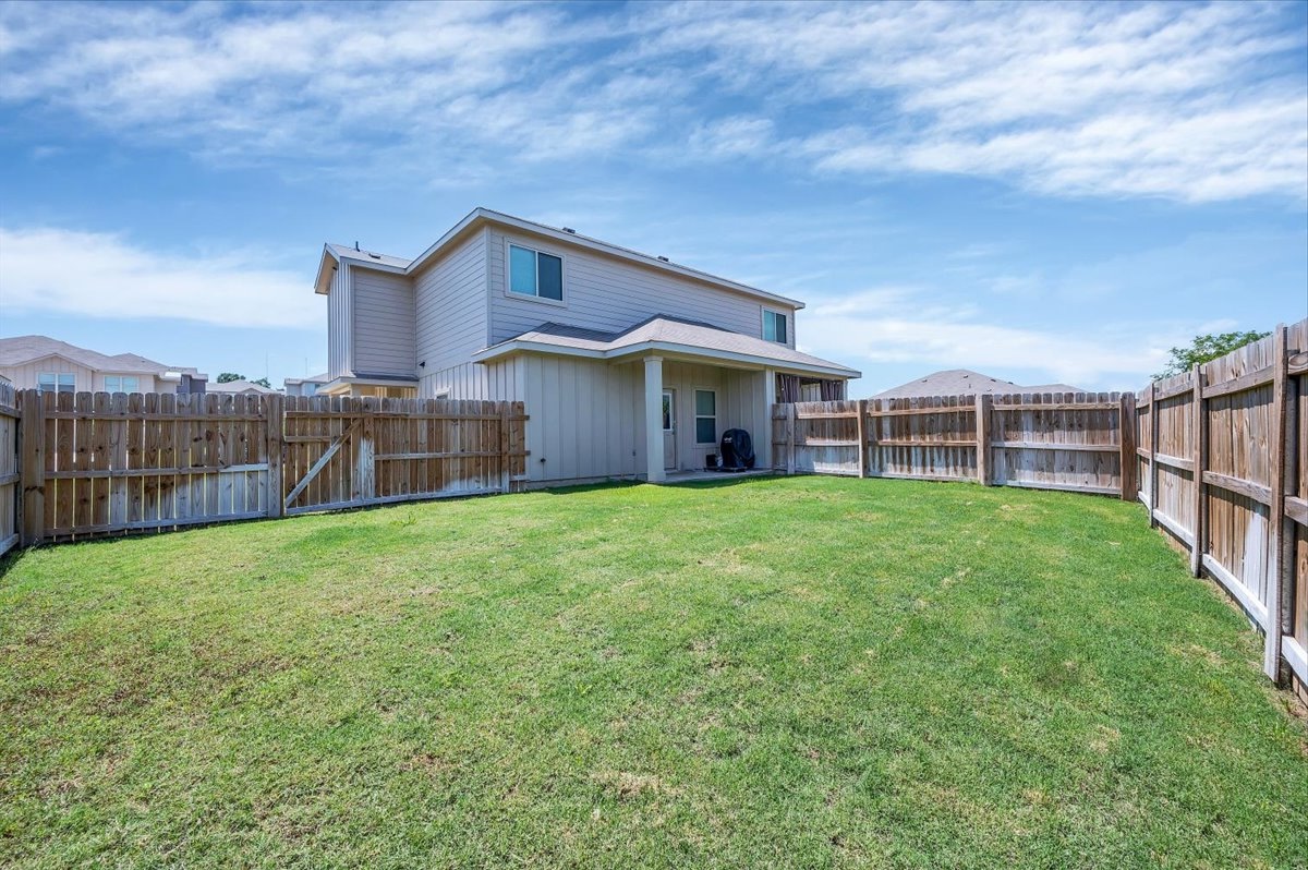 1202 Garland Road Georgetown, TX 78626 - Photo 6 of 28 Expansive fenced backyard with a manicured lawn, featuring a covered patio area and a two-story exterior