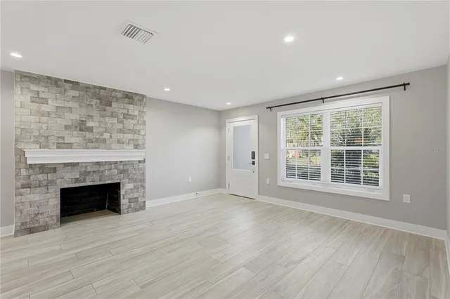 a view of empty room with wooden floor and fireplace