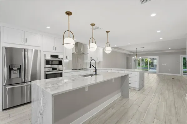 a kitchen with stainless steel appliances granite countertop a sink a oven a refrigerator and wooden floor