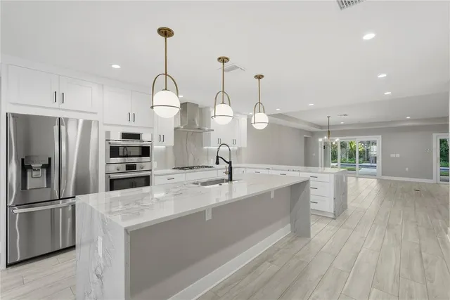 a kitchen with stainless steel appliances granite countertop a sink a oven a refrigerator and wooden floor