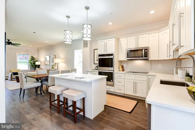 a kitchen with cabinets a sink stainless steel appliances and dining table