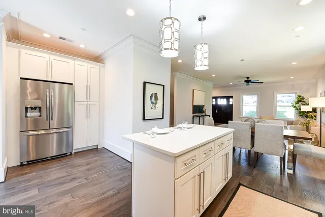 a kitchen with a refrigerator a sink dishwasher a dining table and chairs with wooden floor