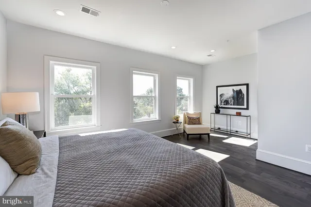 a spacious bedroom with a bed a large window and desk