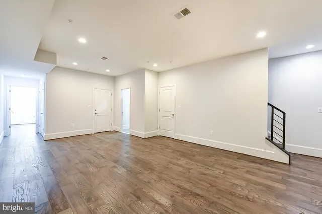 an empty room with wooden floor and natural light