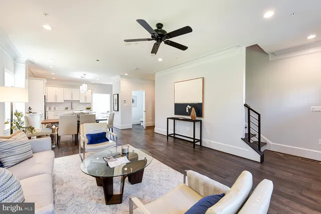 a living room with furniture and kitchen view with wooden floor