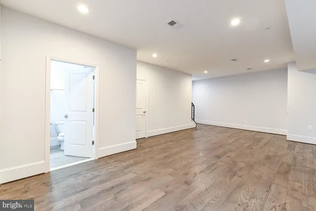 an empty room with wooden floor & cabinet and a window