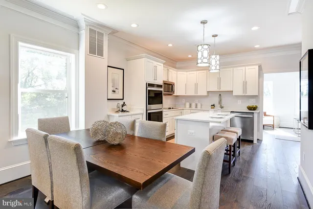 a kitchen with stainless steel appliances granite countertop a stove a refrigerator a kitchen island a dining table and chairs