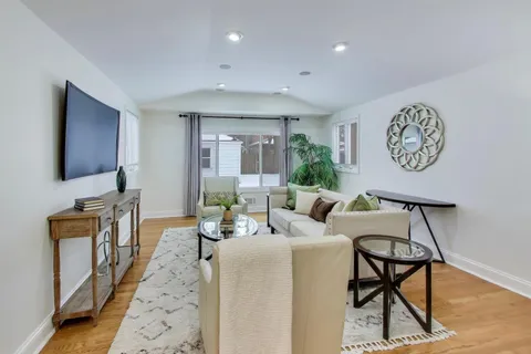 a living room with furniture a flat screen tv and kitchen view