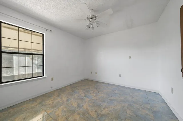 an empty room with a ceiling fan and window