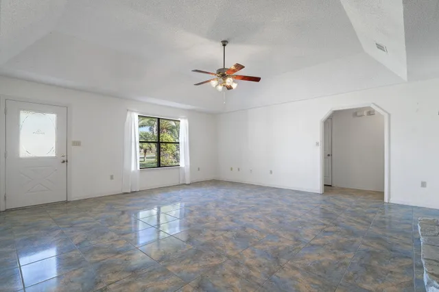 an empty room with windows and fan