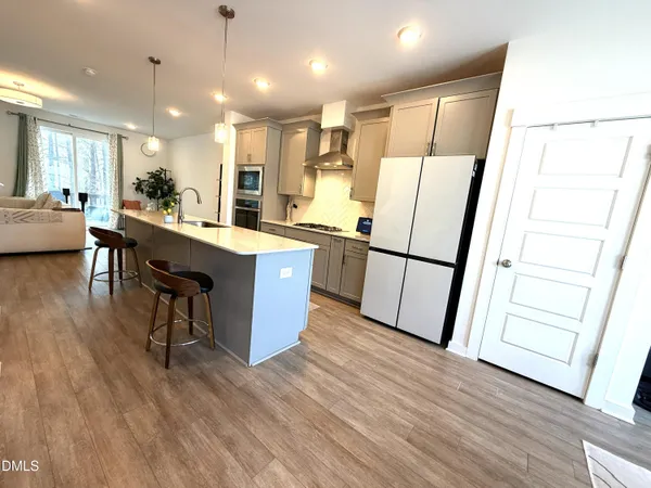 a kitchen with stainless steel appliances granite countertop a refrigerator a sink dishwasher and a stove with wooden floor