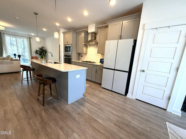 a kitchen with stainless steel appliances granite countertop a refrigerator a sink dishwasher a stove a refrigerator and white cabinets with wooden floor