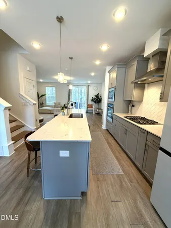 a kitchen with stainless steel appliances granite countertop a sink a stove and a wooden floors