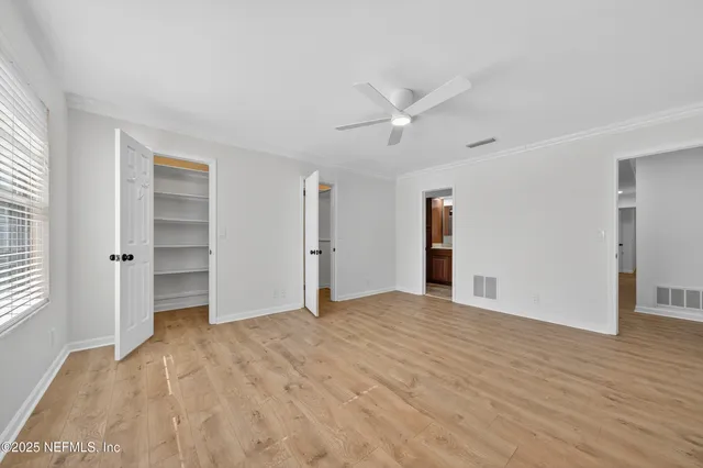 a view of empty room with wooden floor and ceiling fan