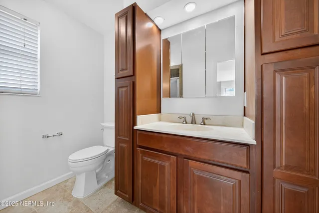 a bathroom with a granite countertop sink toilet and mirror