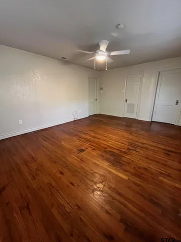 an empty room with wooden floor and fan